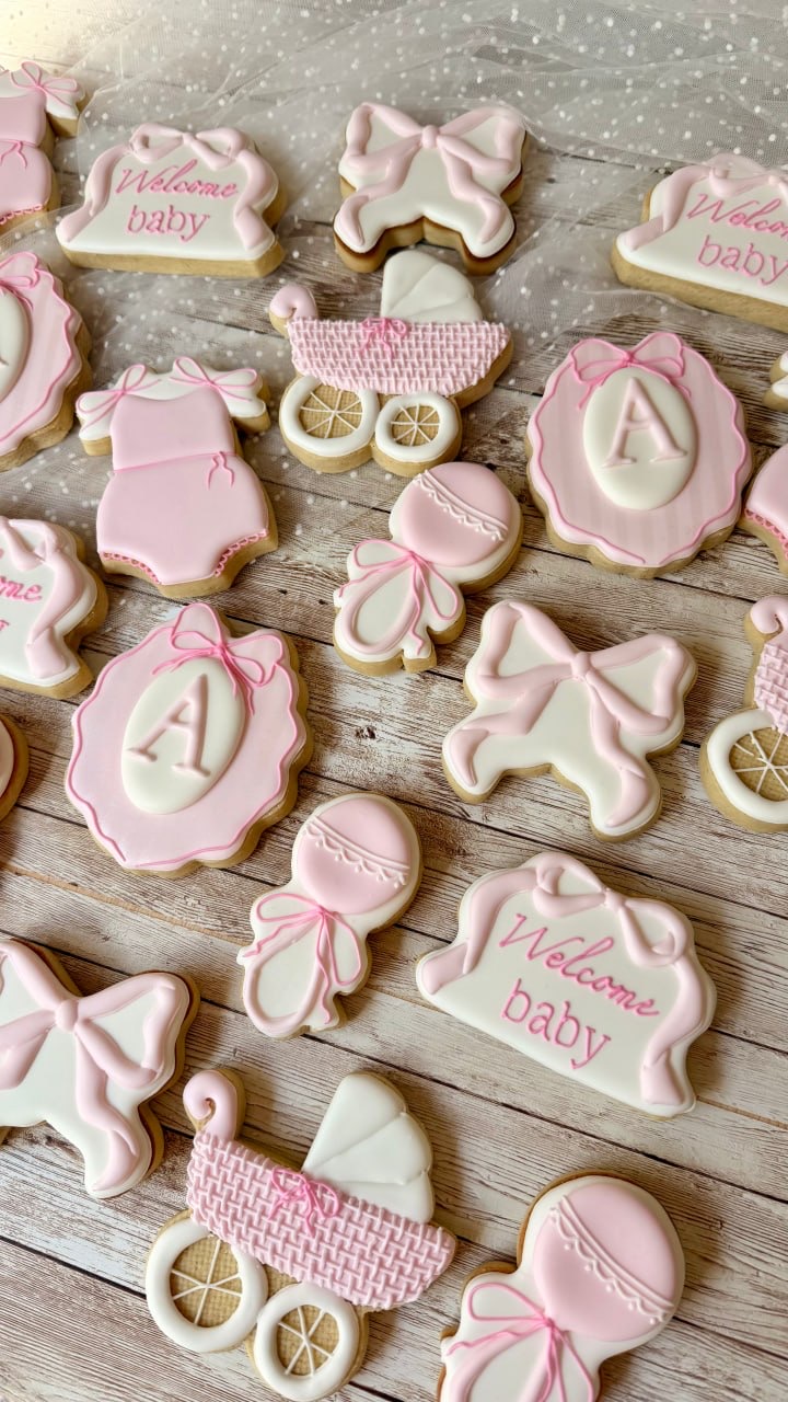 Soft pink baby shower cookies with bows and carriages